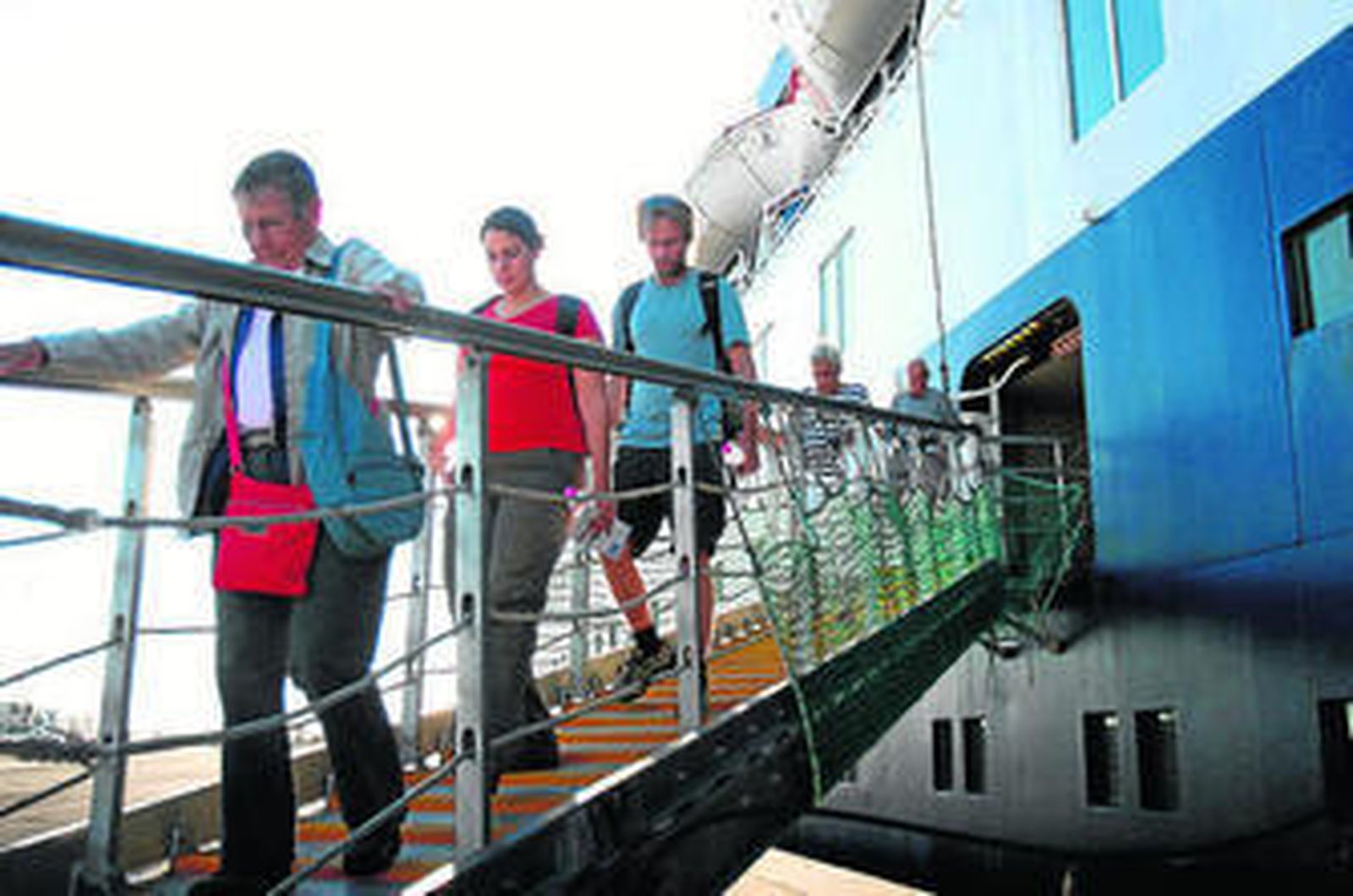 Algunos pasajeros descienden del barco.