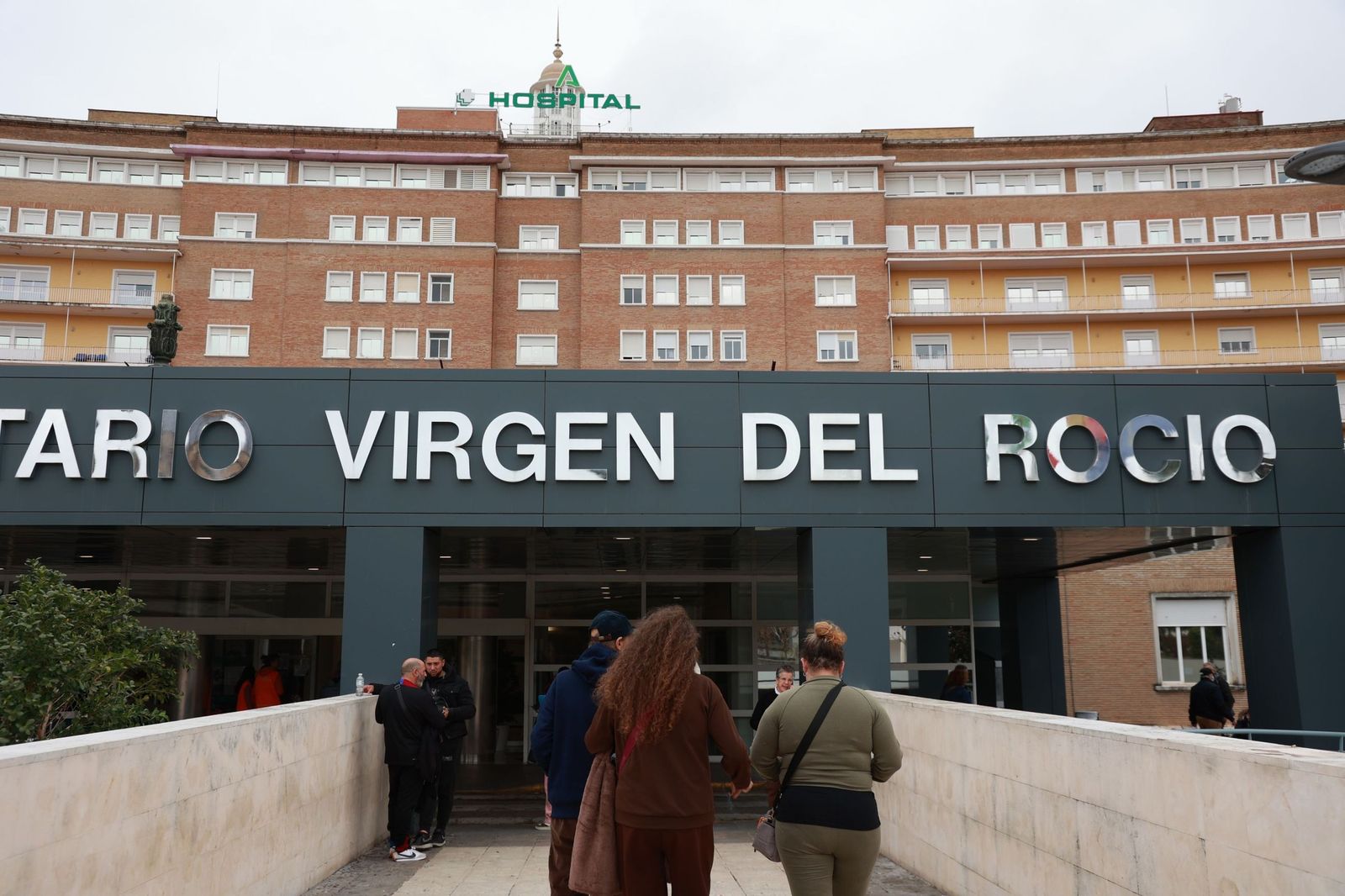 Dos personas se dirigen al acceso principal del  Hospital  Virgen  del  Rocío .