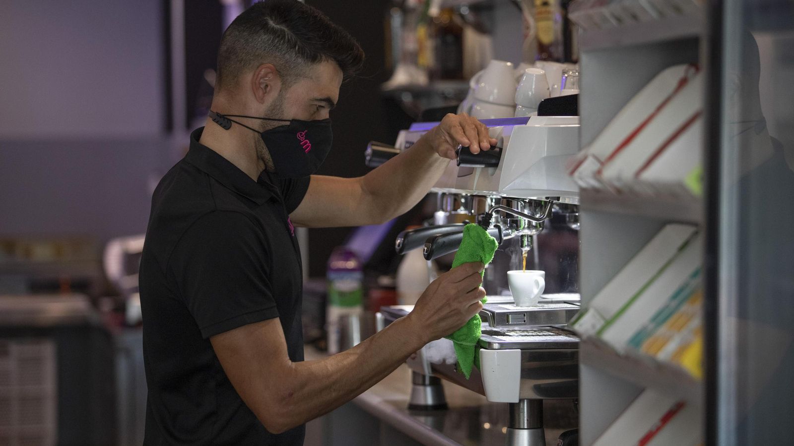 Un camarero limpia la máquina cafetera, una de las principales emisoras de calor en un local de restauración