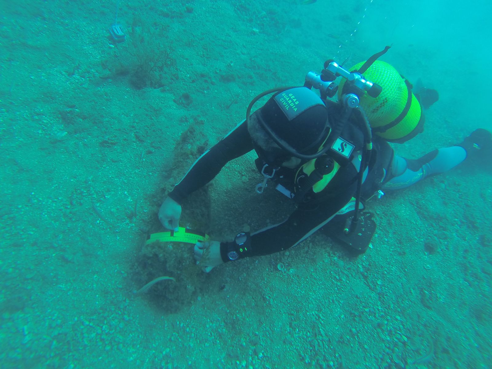 Un agente revisa una pieza de armamento localizada en las profundidades marinas.