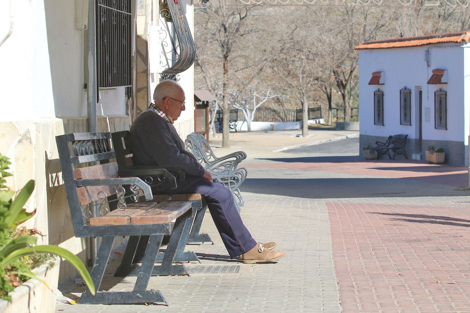 Un hombre sentado en un banco en el núcleo de Ocaña (Las Tres Villas)