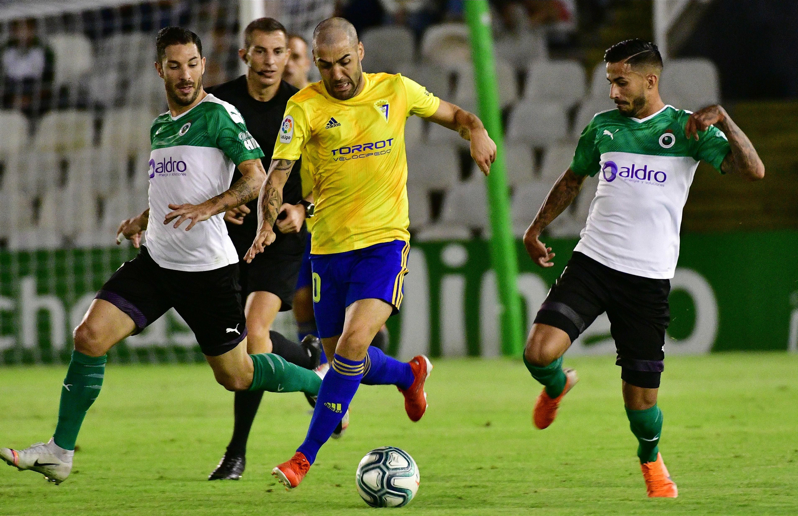 Perea avanza con el balón perseguido por dos defensores del Racing.