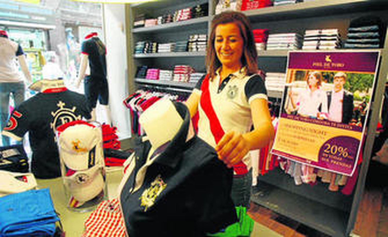 Lourdes Expósito coloca una prenda delante de un cartel que anuncia los descuentos.