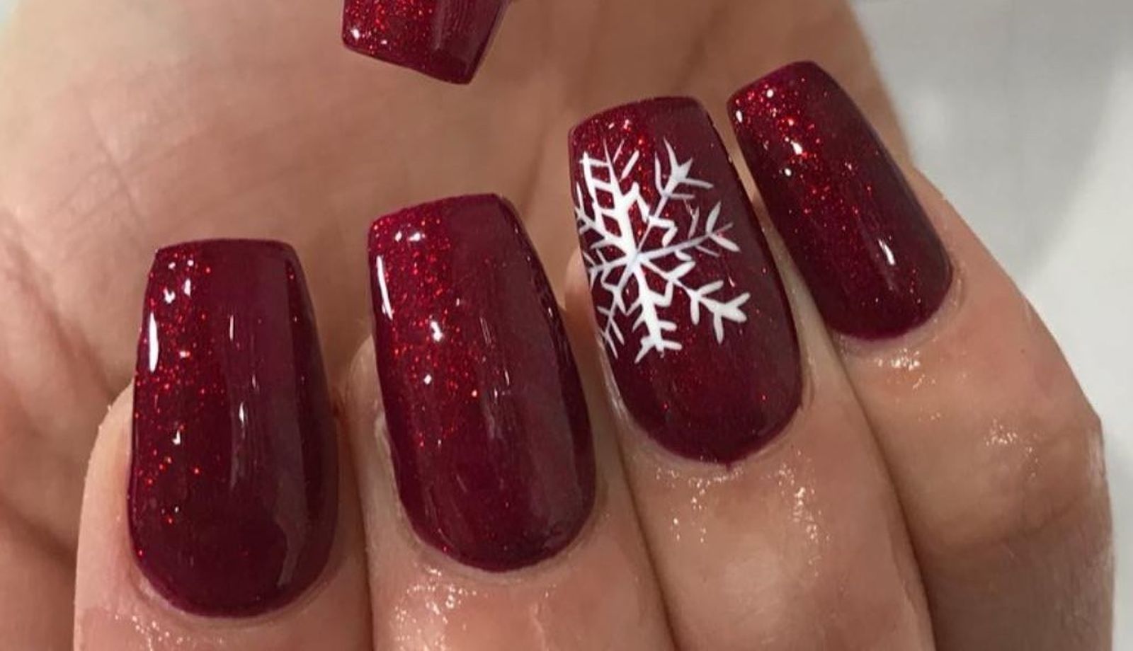 Sencilla manicura roja de purpurina con detalle de copo de nieve de @nails_beauty_salon.