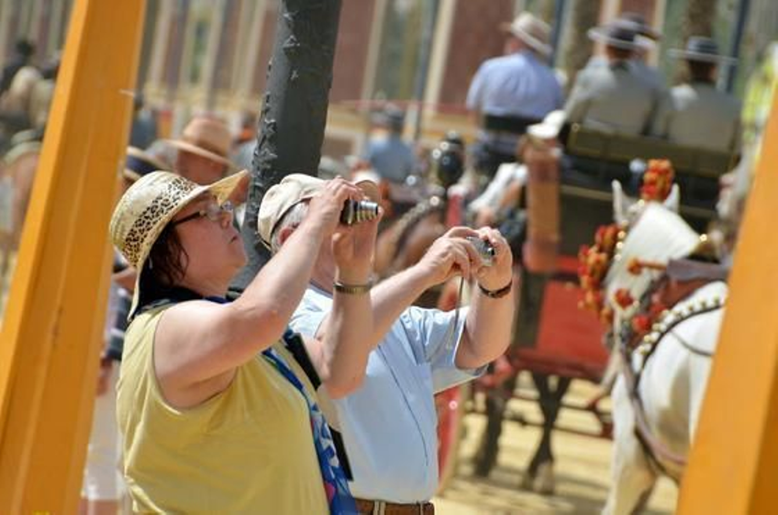 De recuerdo. Dos turistas fotografían un coche de caballos, ayer, por el paseo principal del Real de la Feria.  Foto: Manuel Aranda