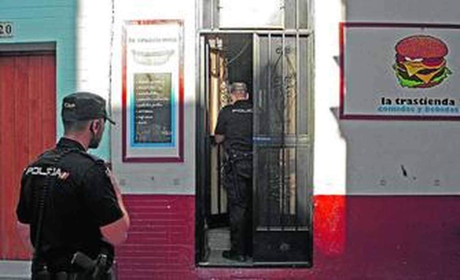 Dos policías examinan la puerta de la hamburguesería, que ayer fue forzada.
