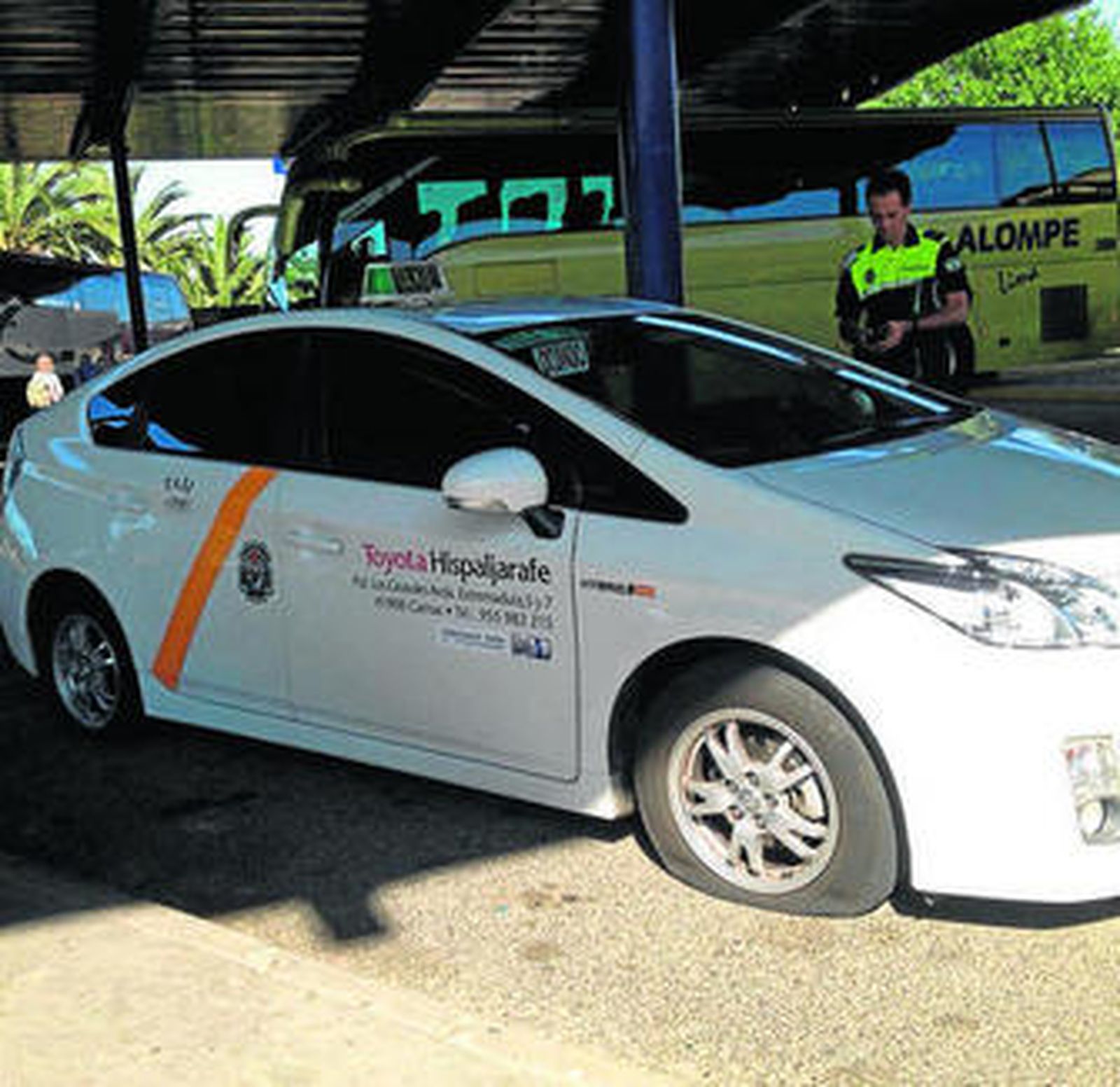 El taxi, con las ruedas pinchadas y la Policía detrás.