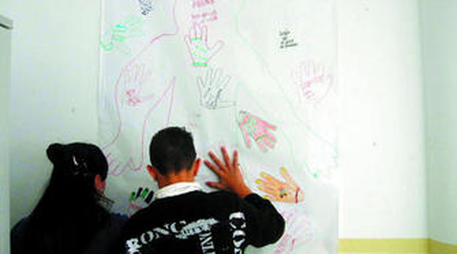 Dos alumnos delante de un mural en el que explican sus objetivos a corto plazo.