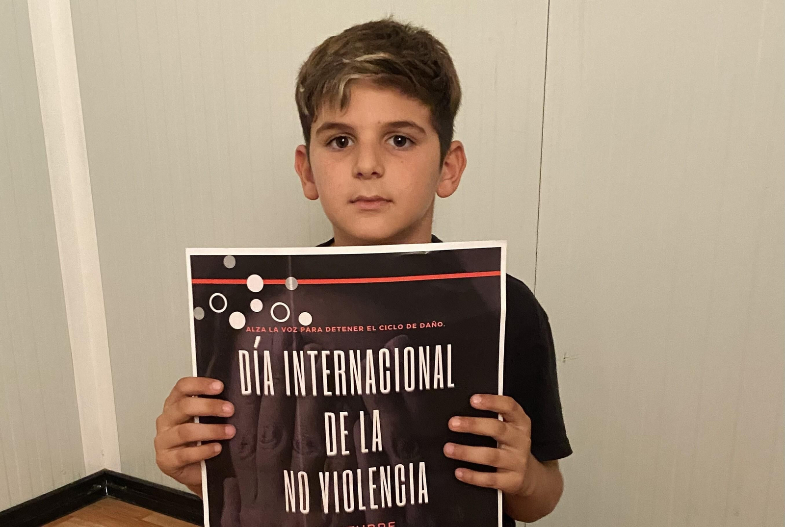 Un niño del barrio de La Cimilla muestra el cartel del evento.