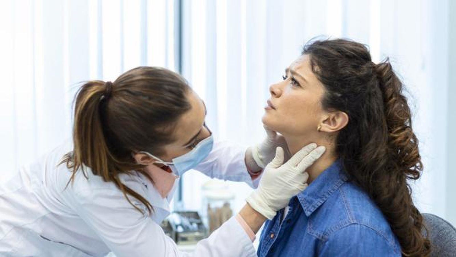 Médico examinando garganta de una paciente.