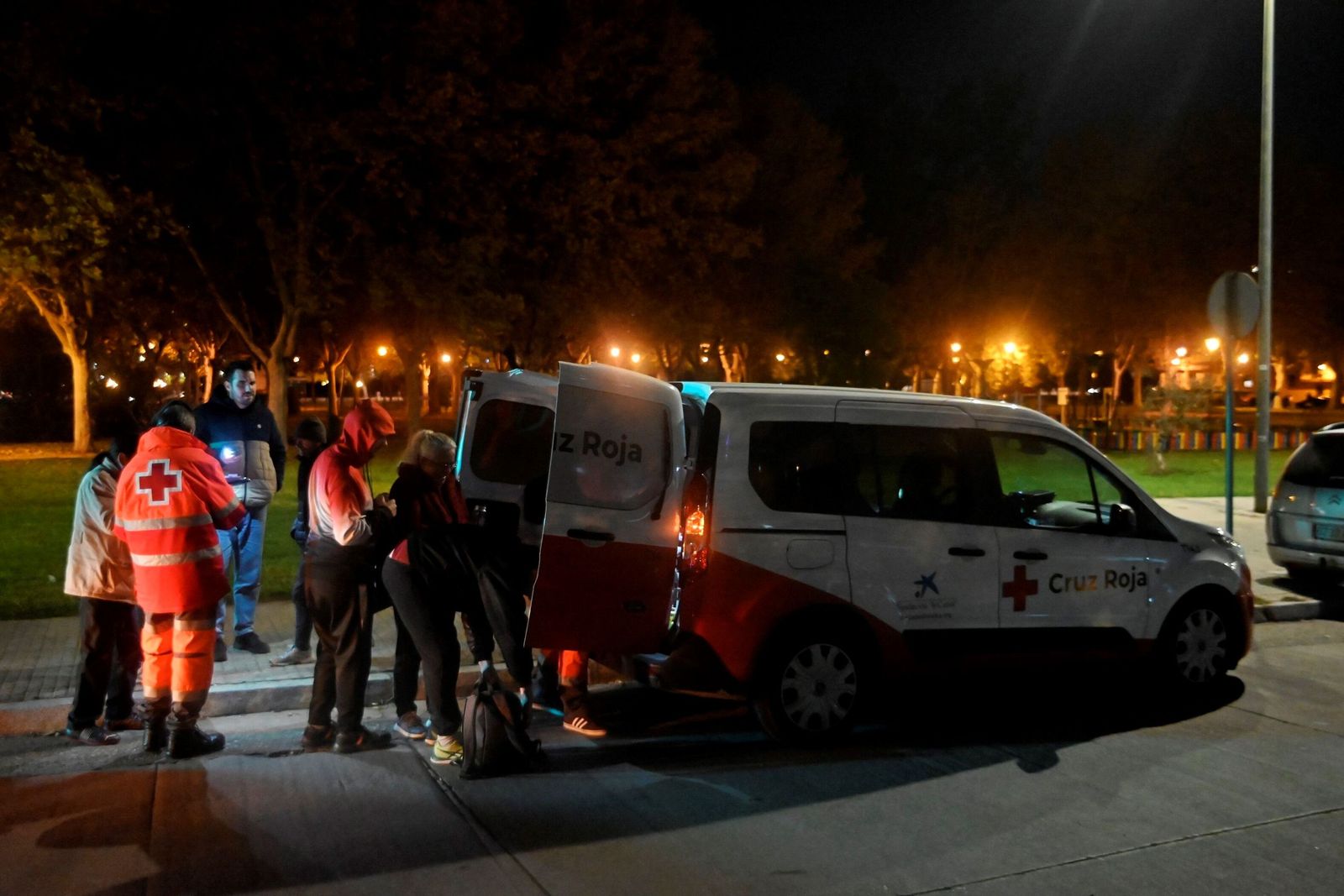 Una furgooneta de Cruz Roja reparte comida entre personas sin hogar.