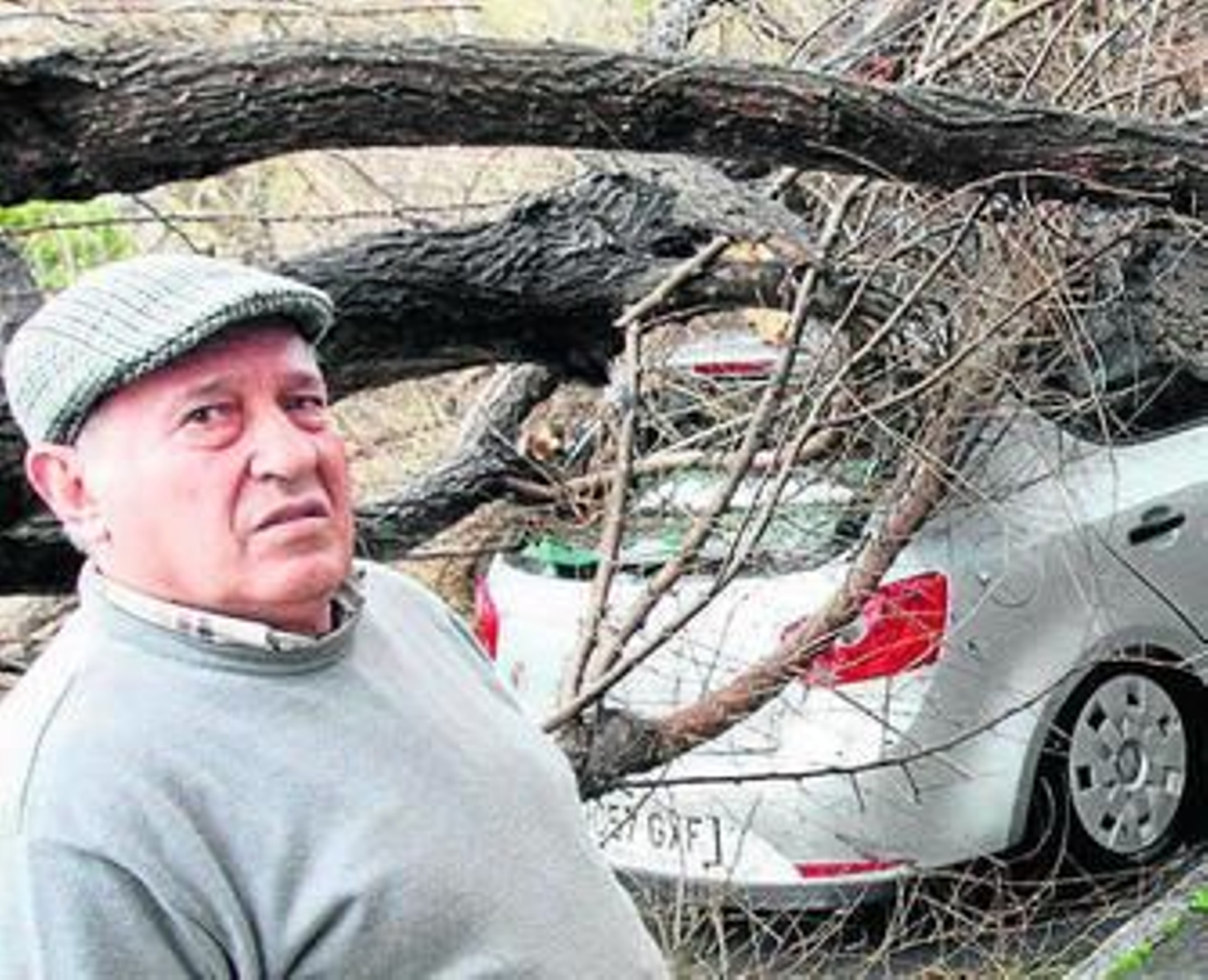 Manuel García, ante su coche destrozado por el árbol.