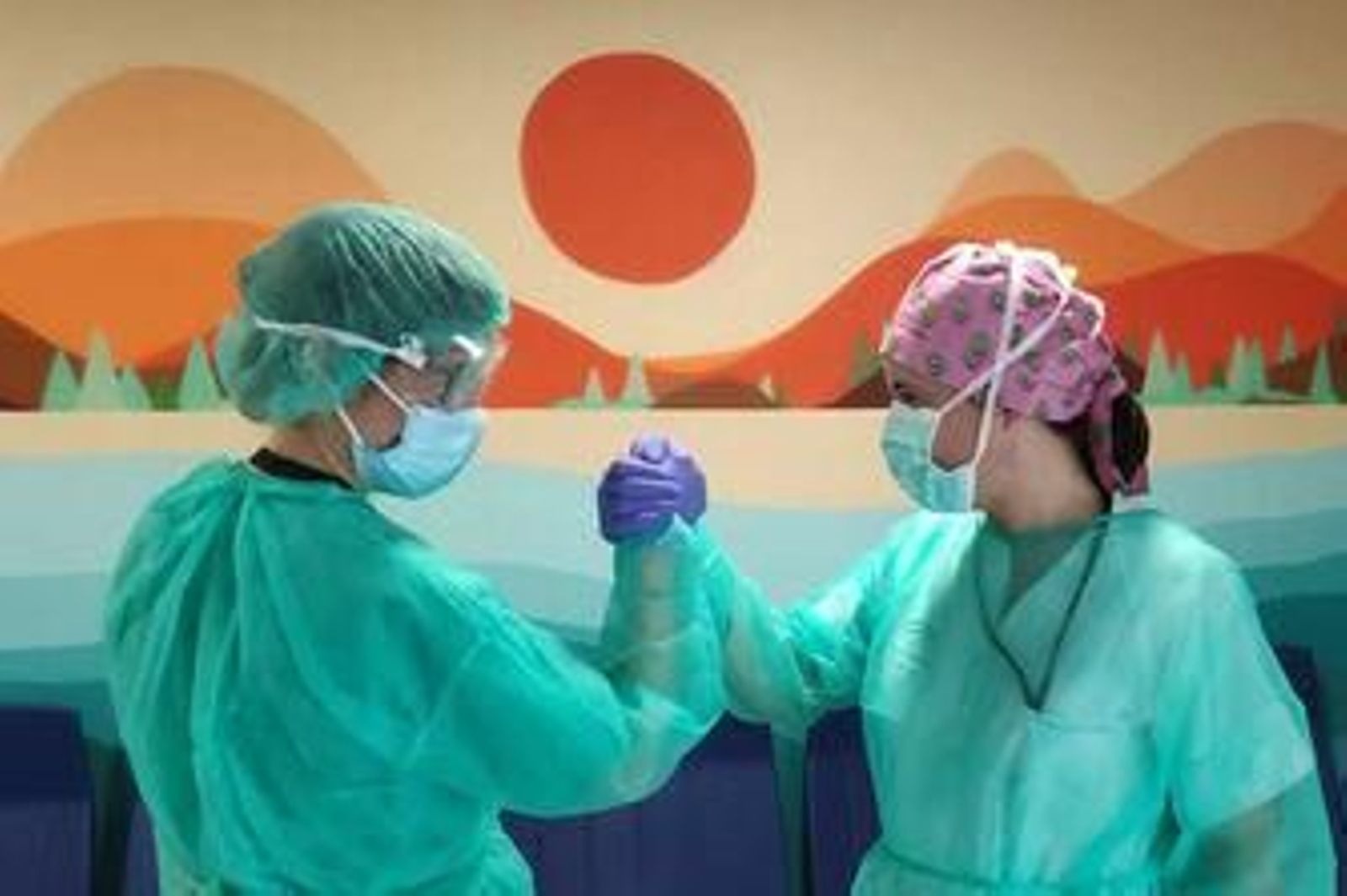 Dos enfermeras se dan la mano en un hospital.