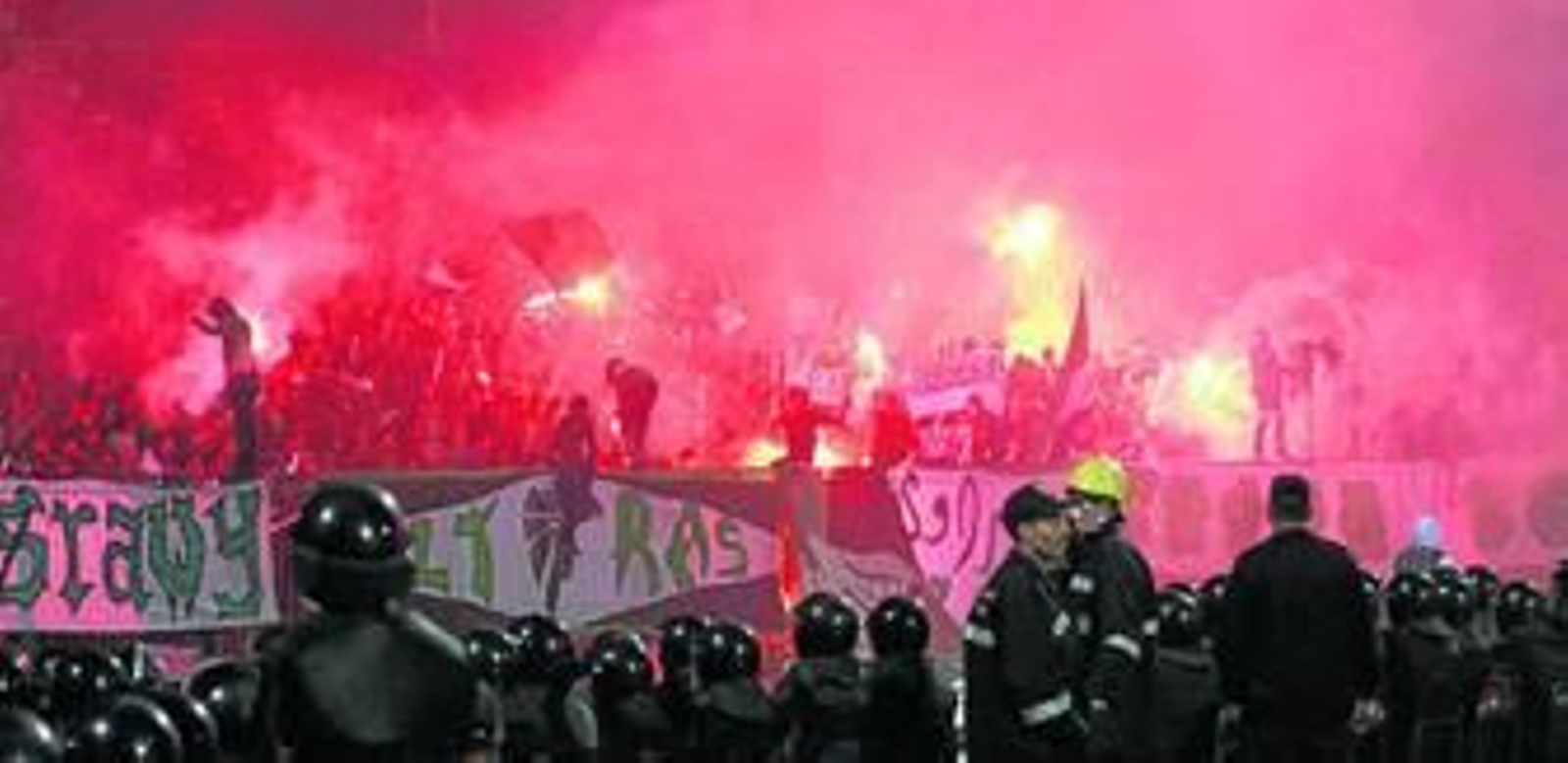 Los seguidores del Al Masri encienden bengalas durante el partido ante la atenta mirada de la Policía.