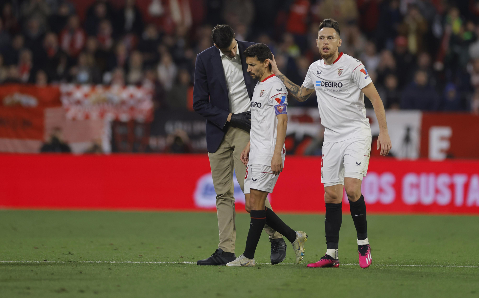 Ocampos consuela a Jesús Navas mientras es atendido por el médico del Sevilla.