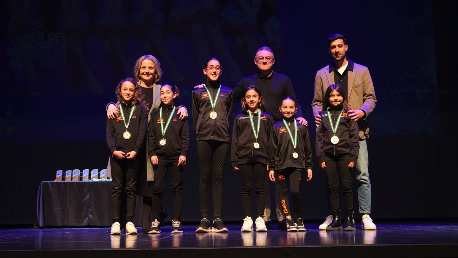 Un grupo de deportistas de uno de los clubes premiados reciben en el escenario sus correspondientes medallas.