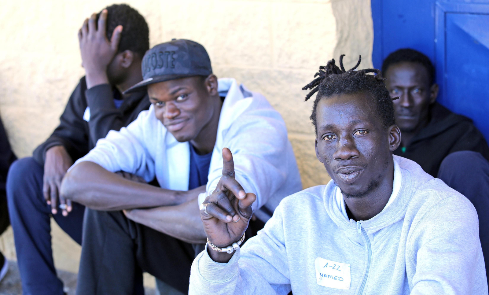 Un grupo de inmigrantes sentados en las afueras del pabellón polideportivo Kiko Narváez.