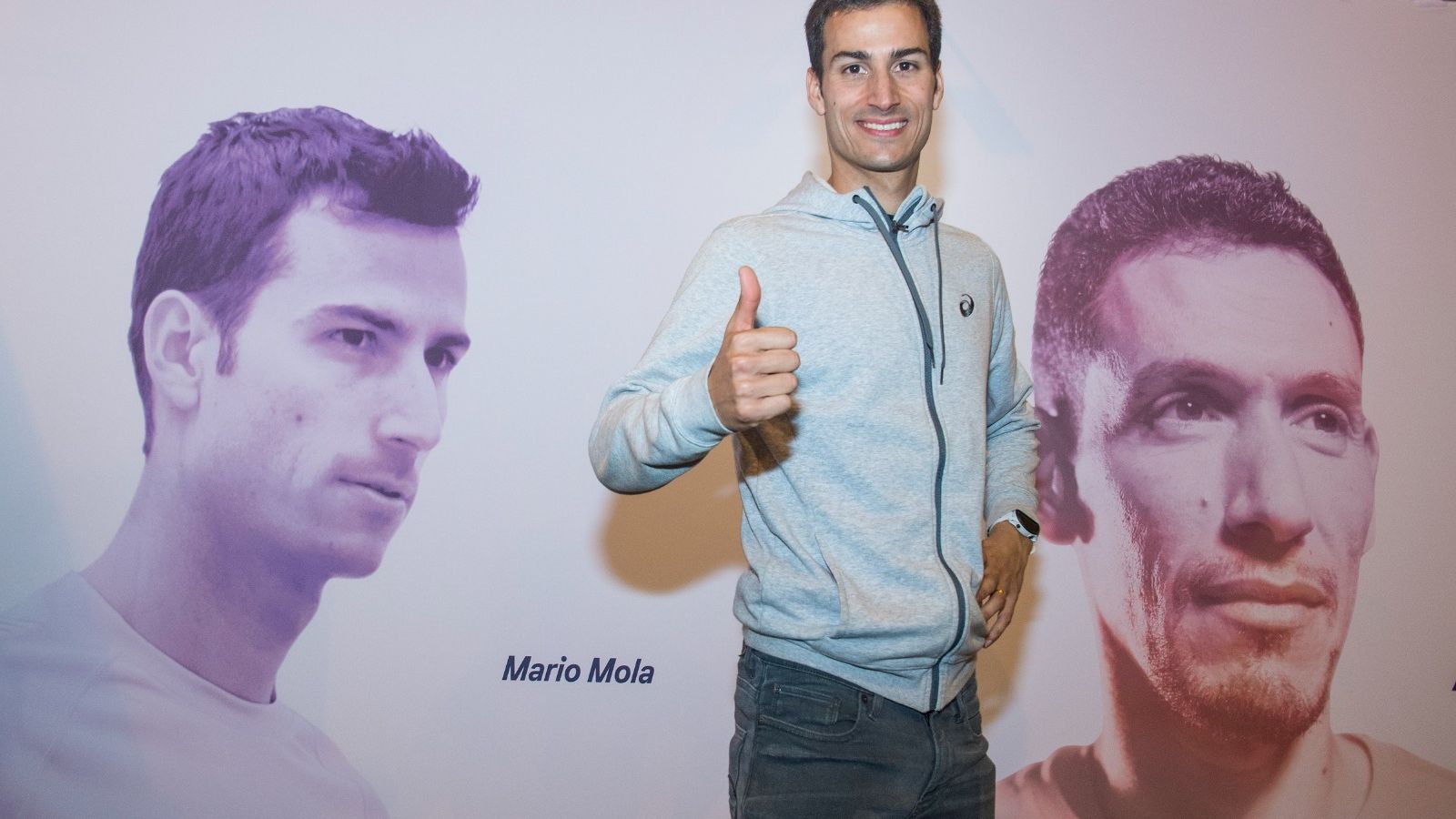 Mario Mola posa en un stand de la Feria del Corredor en una fotografía suya y otra de Ayad Lamdassem.