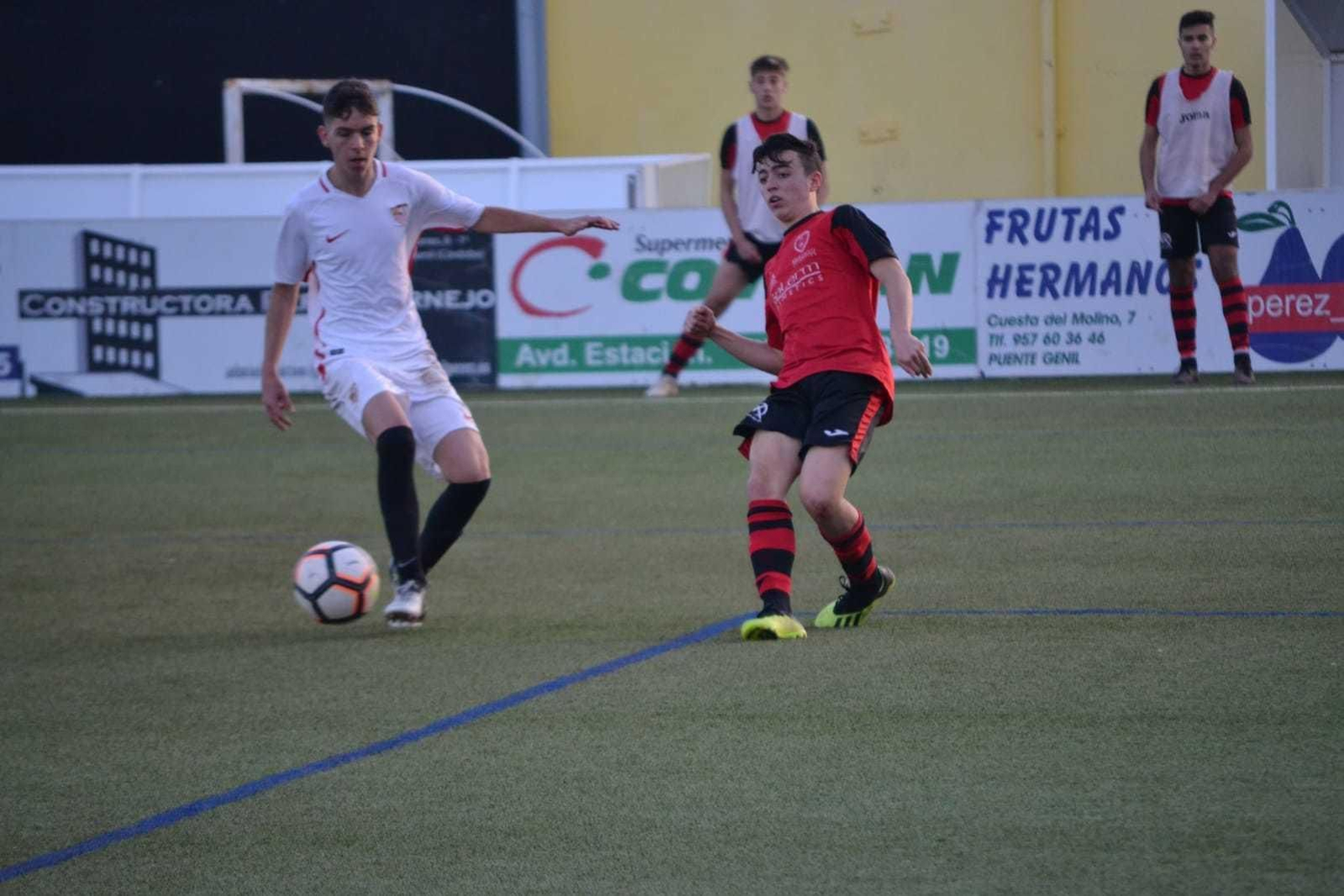 Un jugador del Puente Genil corta el avance de un jugador del Sevilla.