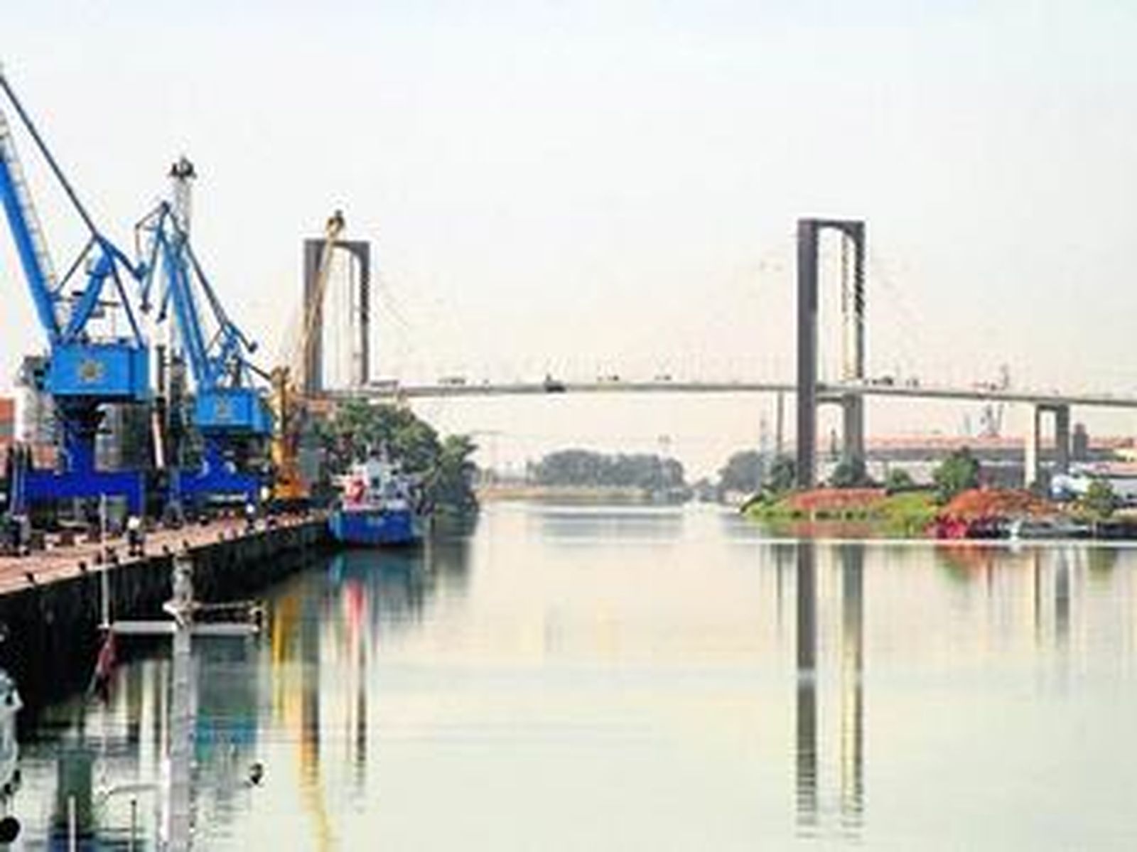 Una vista del Guadalquivir con los muelles del Puerto a un lado y al fondo el Puente del V Centenario.