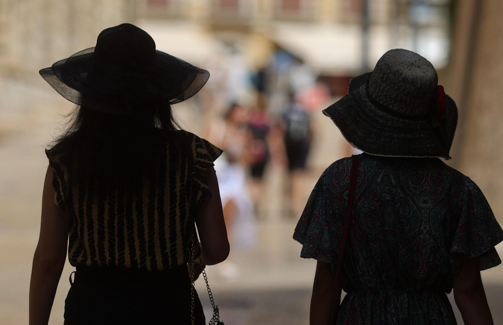 Dos mujeres caminan bajo la sombra en una céntrica calle de Málaga
