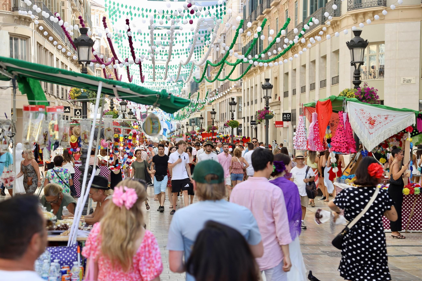 Ambiente en el Centro durante la Feria de Málaga, donde no faltan gorras, sombreros y abanicos para combatir el calor.