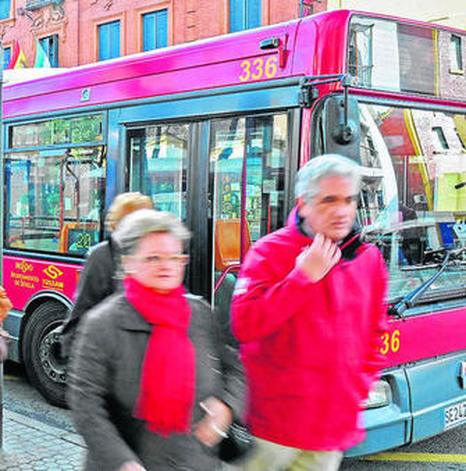 Varias personas caminan junto a un autobús de Tussam.