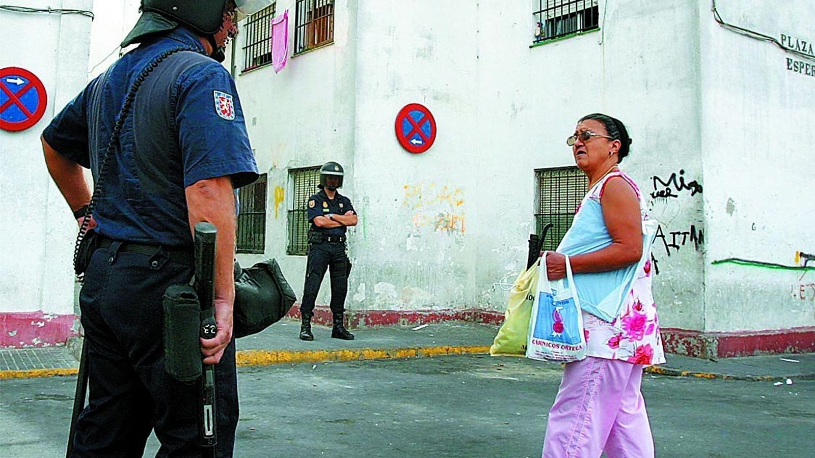 Una vecina pasa por la barriada, llena de policías, en una imagen de archivo.