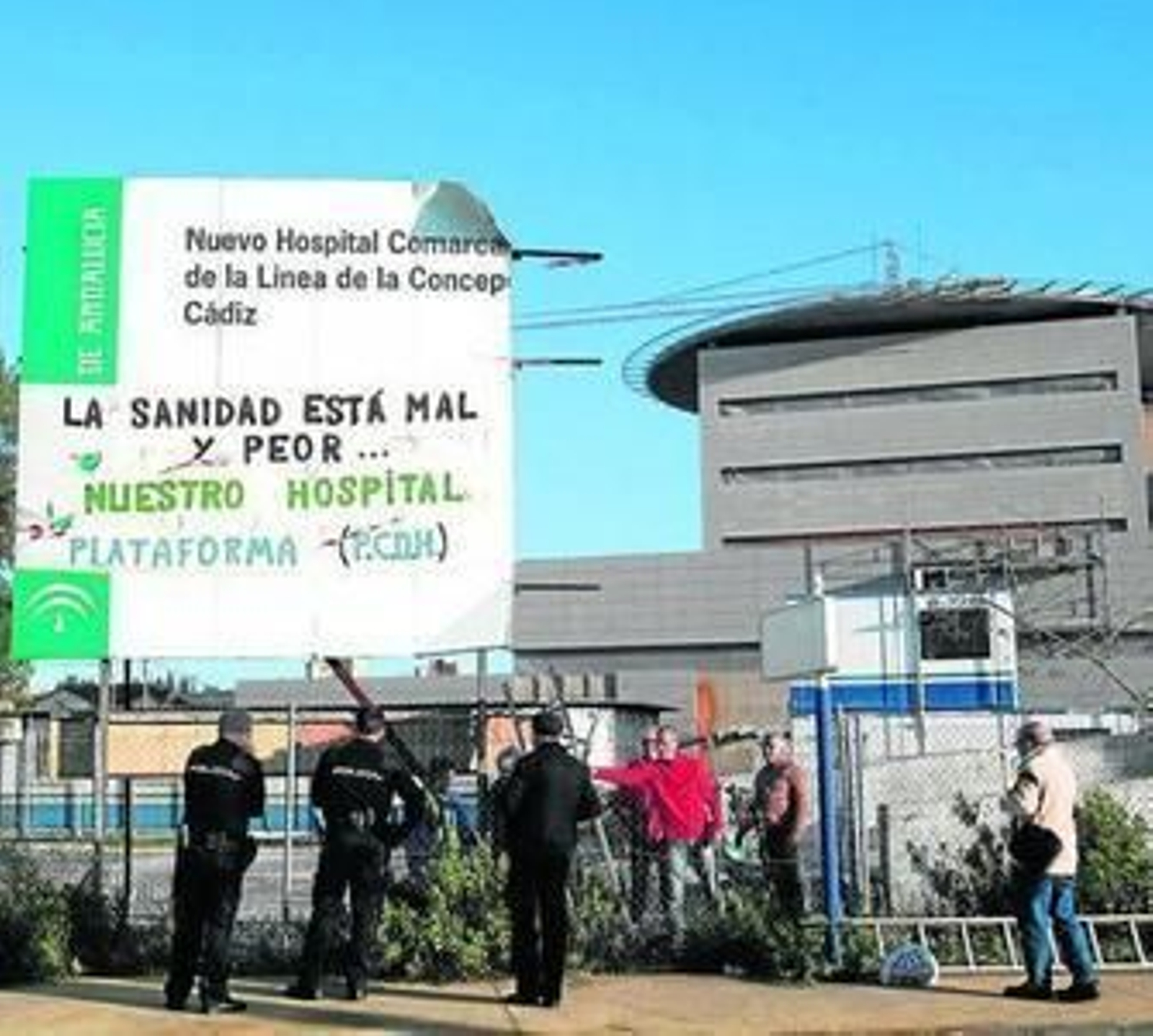 Miembros de la Plataforma en defensa del hospital y policías, tras colocar una pancarta en las obras en 2013.