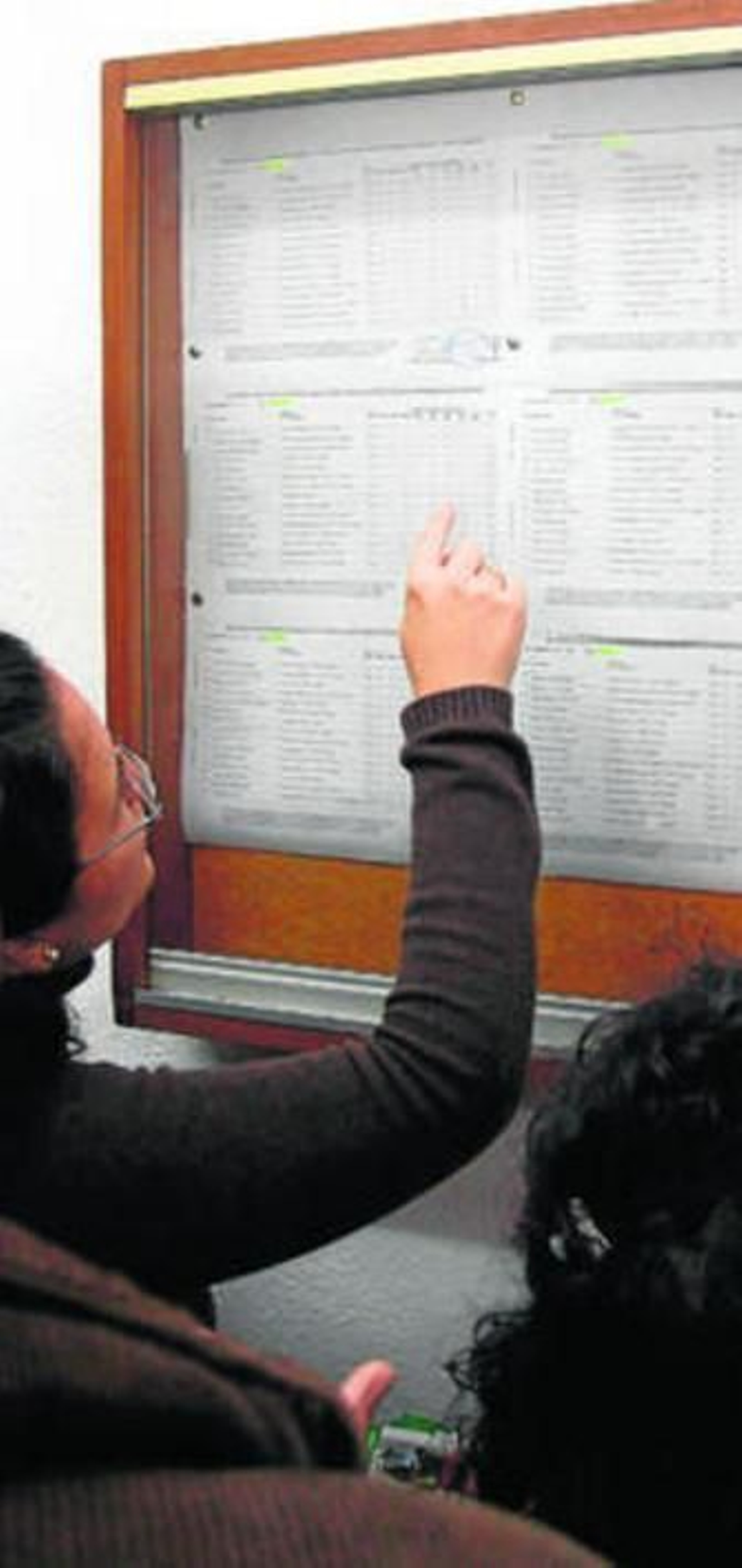 Los padres comprueban el listado de admisión de alumnos en un colegio.