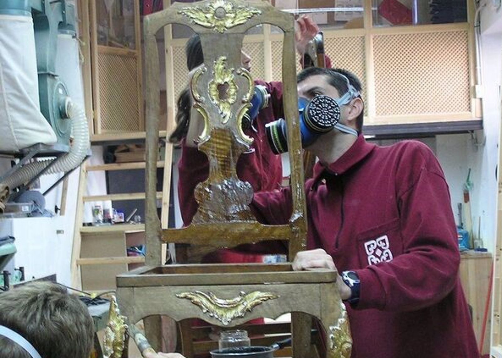 Dos alumnos de restauración trabajan en una silla antigua