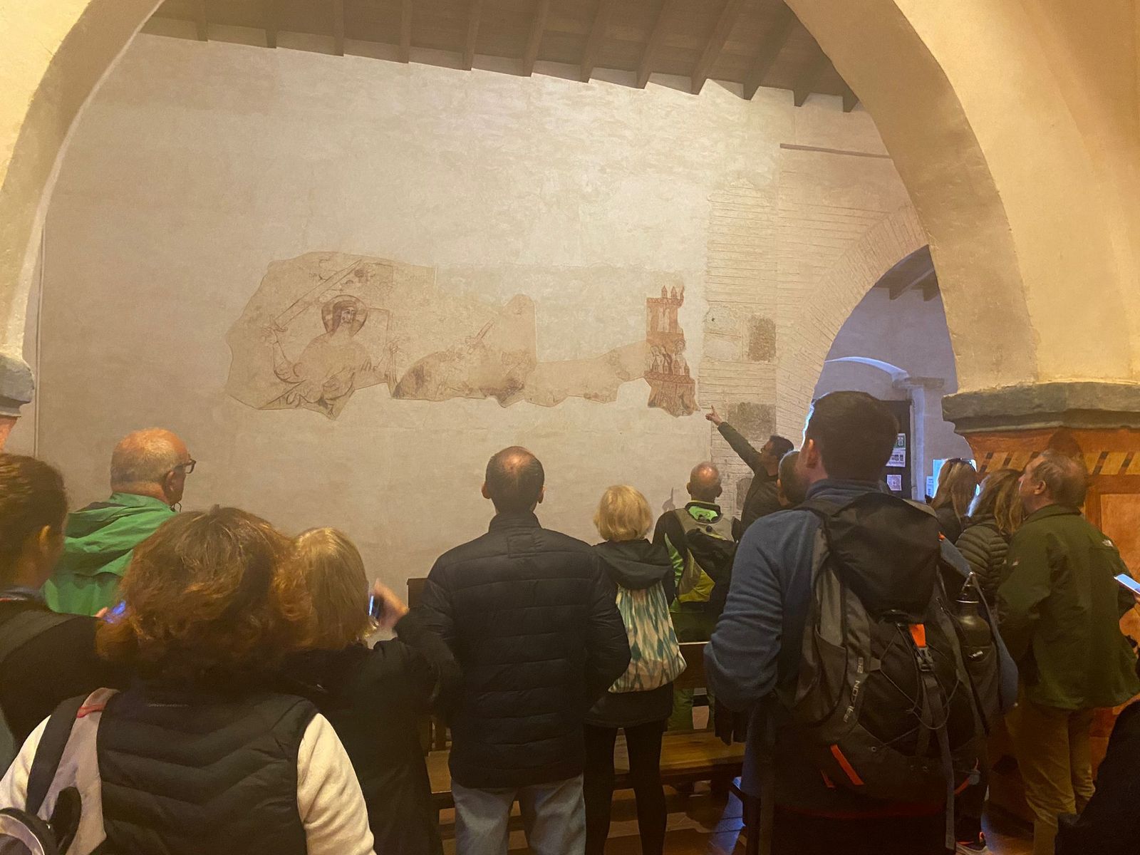 Grupo de turistas mira parte de un fresco.