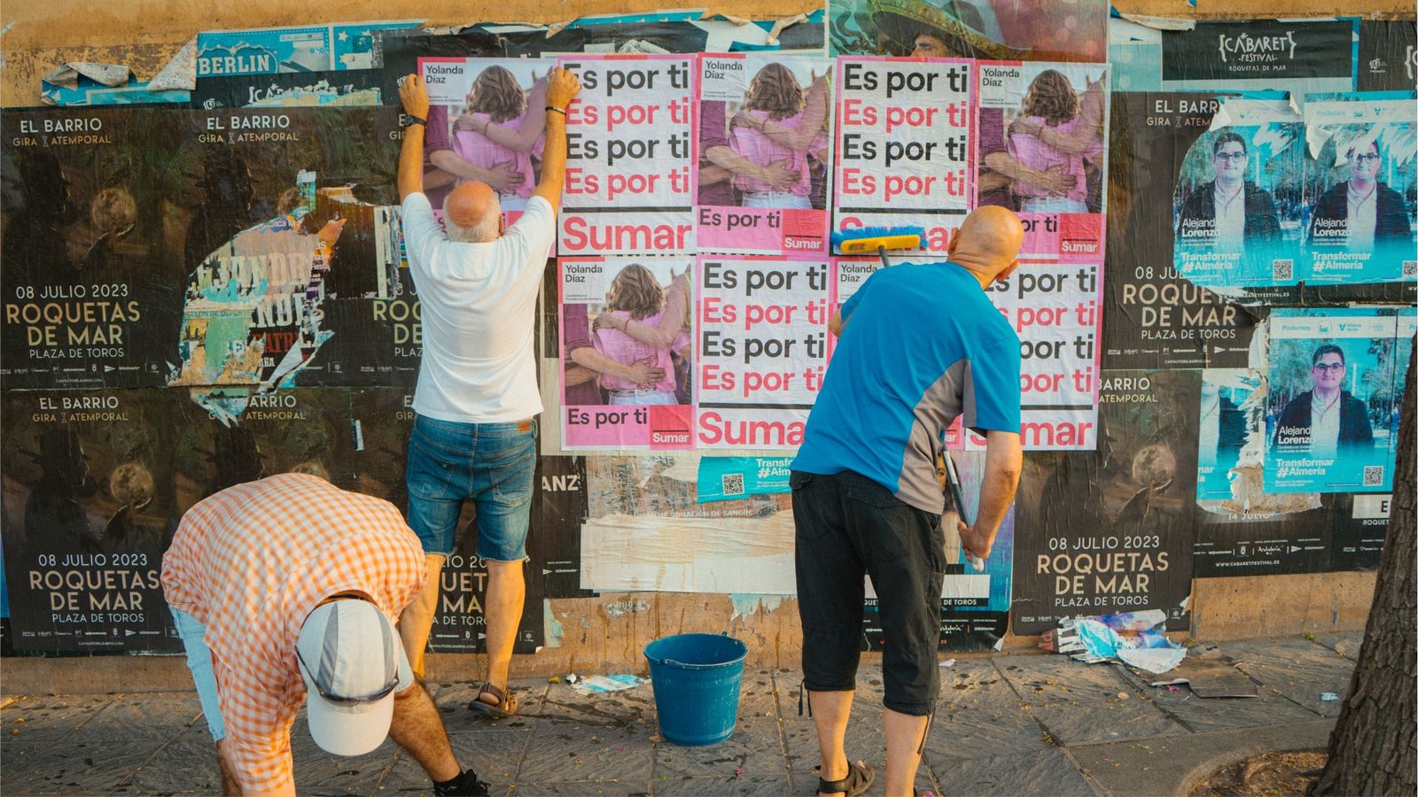 Voluntarios de Sumar pegando carteles en Almería