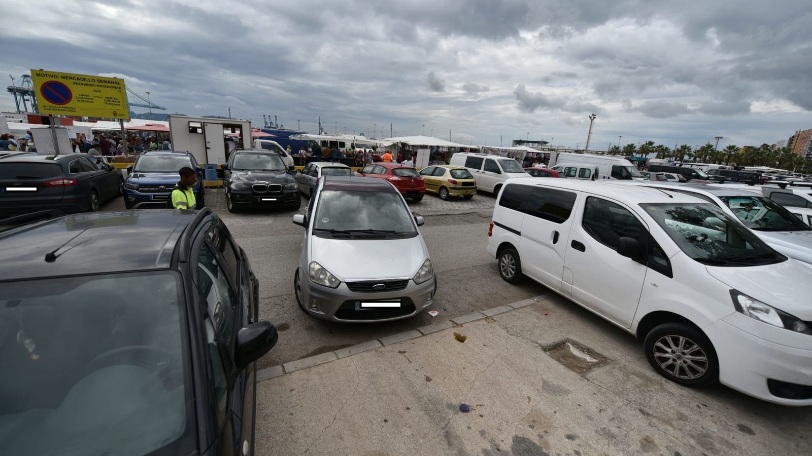 Un turismo aparca en el Llano Amarillo con el mercadillo al fondo.
