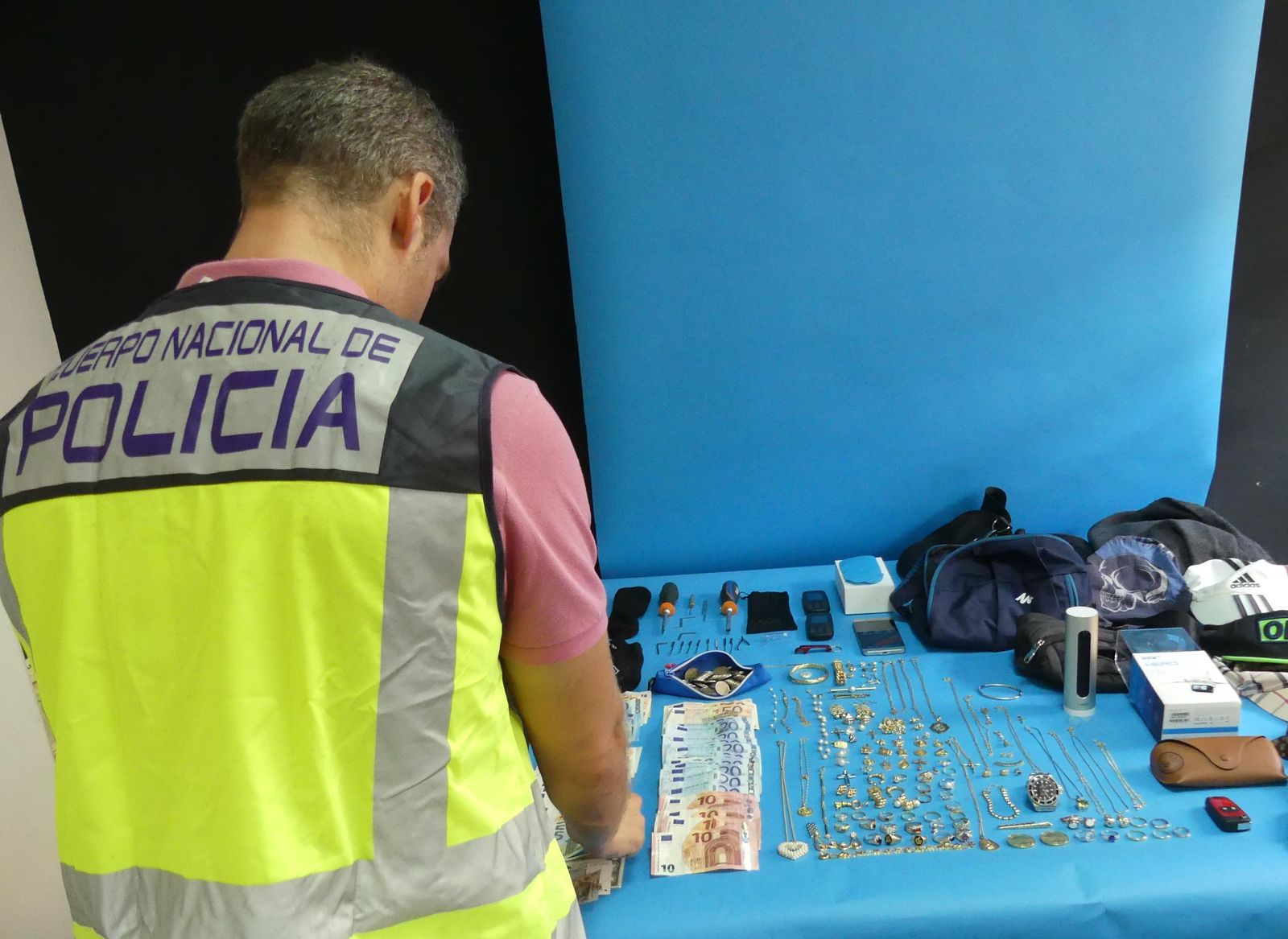 Un policía, junto con los efectos recuperados.