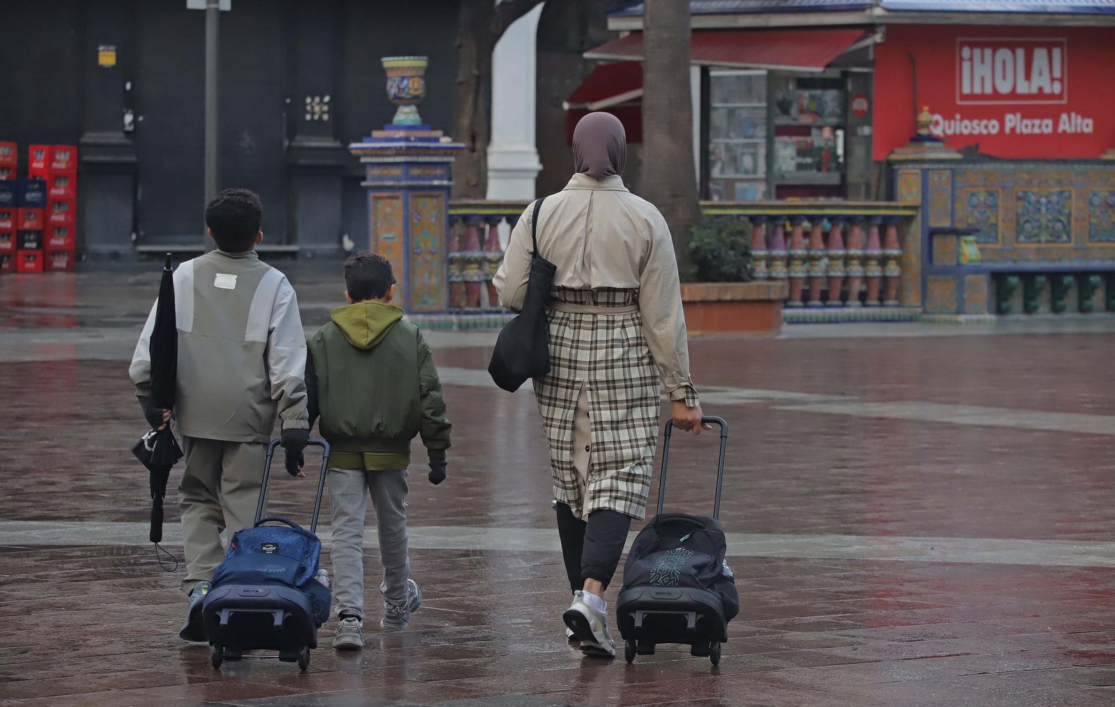 Una madre con sus dos hijos camino del colegio por la Plaza Alta de Algeciras.