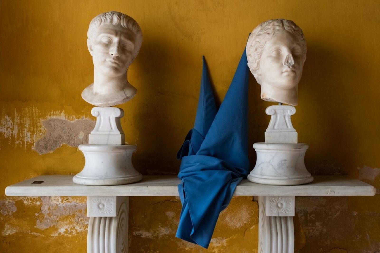 Dos nazarenos de San Esteban dejan sus capirotes junto a unos bustos romanos mientras forman la cofradía.