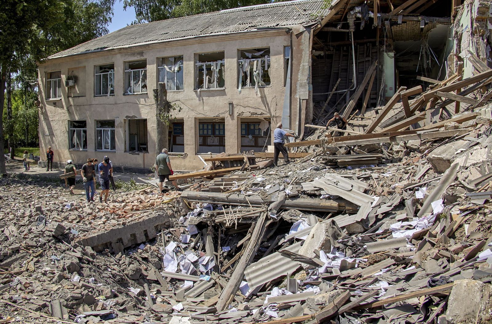Lugareños limpian los escombros tras un ataque con misiles en una pequeña localidad cercana a Jarkov.