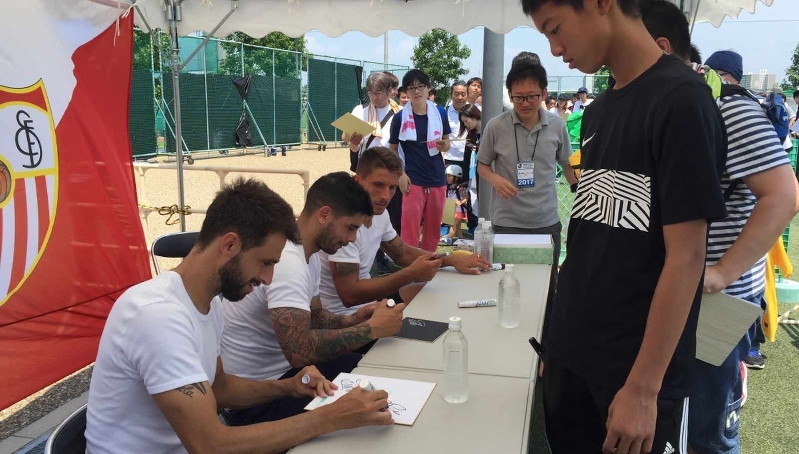 Los jugadores sevillistas Pareja, Banega y Carriço firman autógrados para los aficionados en Osaka.