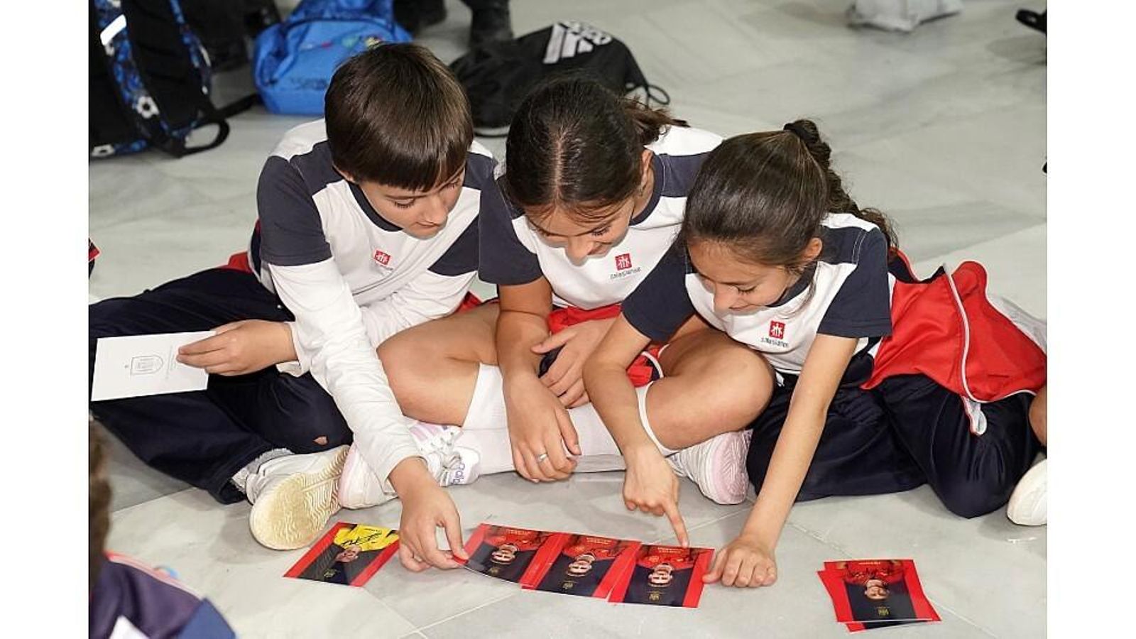Tres alumnos observan las fotografías de los futbolistas.