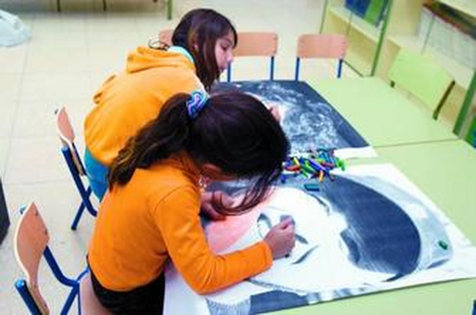 1. Dos alumnas del Ceip Nuestra Señora de la Paz colorean las fotos ampliadas de miembros de la comunidad educativa en el taller intercultural de retratos.2. Otro alumno imprime sus manos en el muro del colegio. 2. Macarena Mijes, Emilio Vela y Javier Fito, ante los retratos que iban a pintar los participantes del taller.