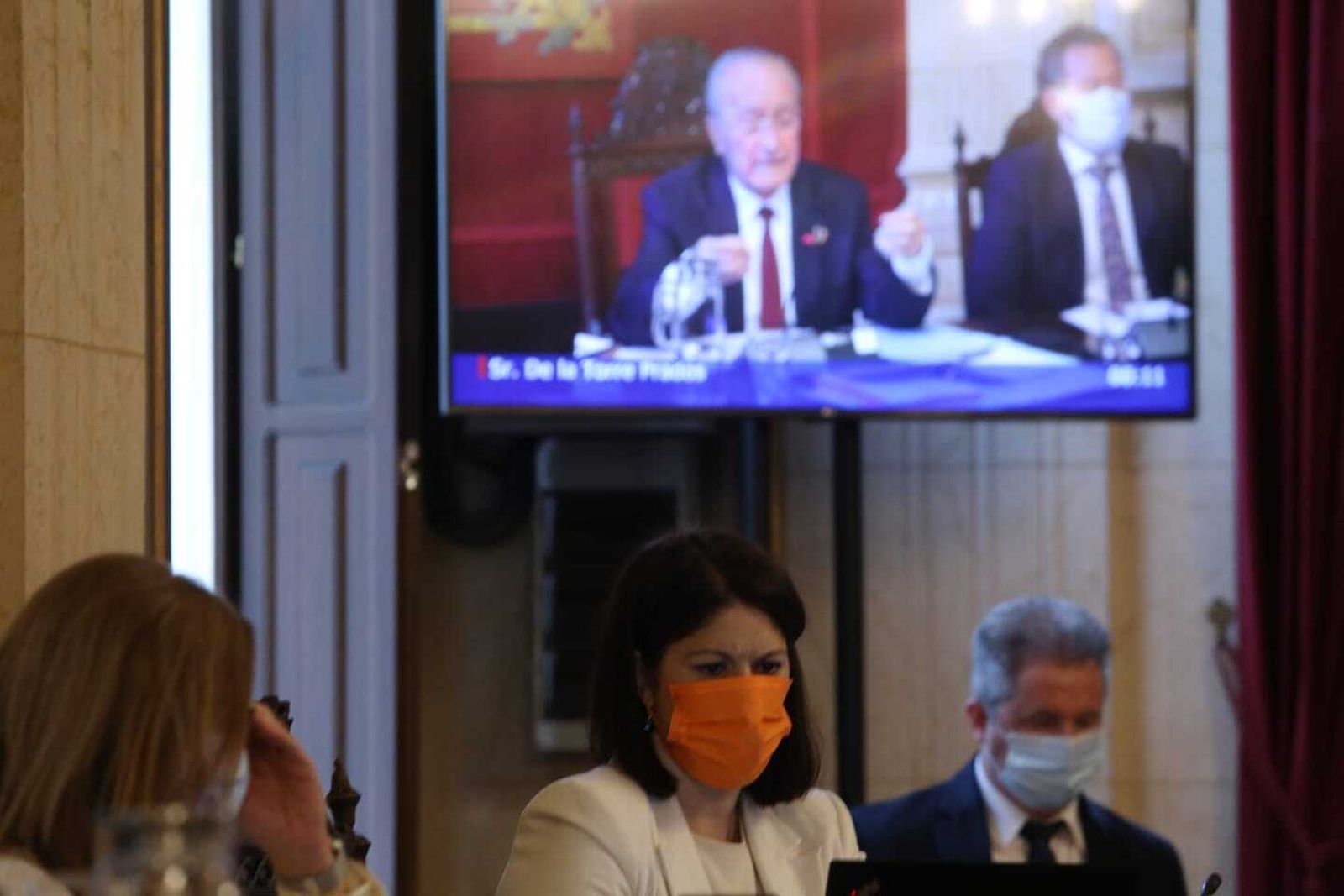 Noelia Losada, en primer plano, con el alcalde, Francisco de la Torre, en una pantalla al fondo.