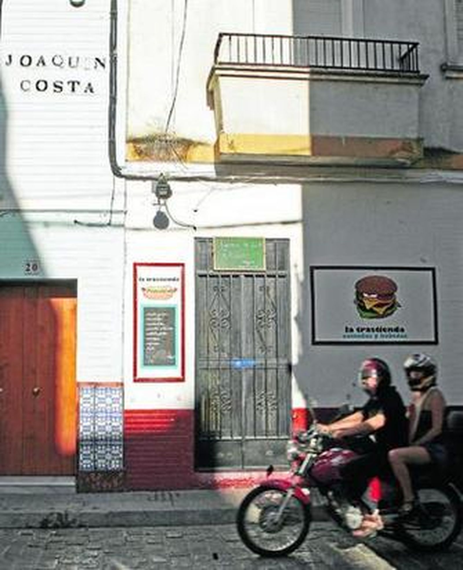 Una moto pasa por la puerta de la hamburguesería que regentaba la víctima.