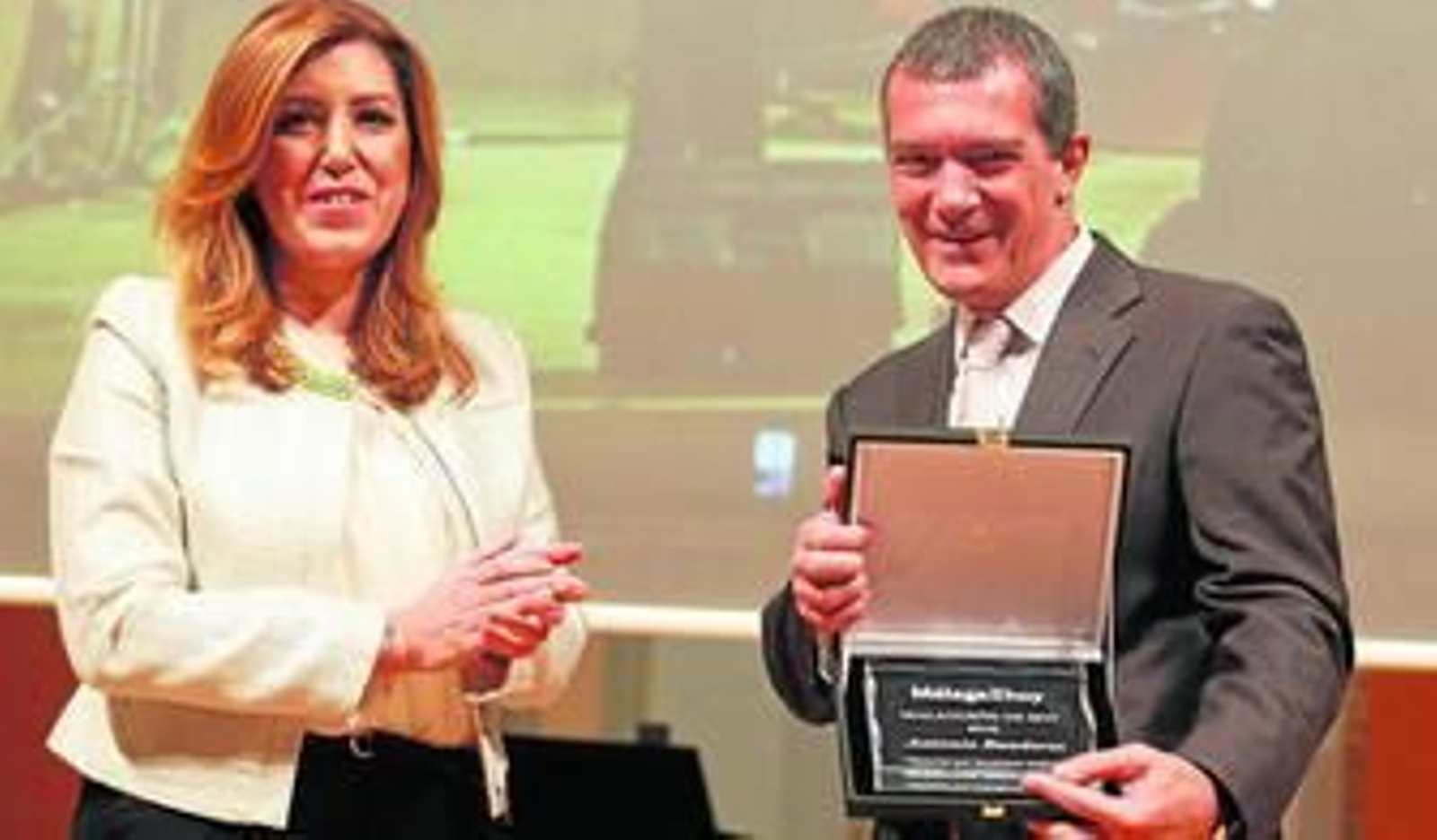 Banderas recoge la placa de reconocimiento de manos de la presidenta de la Junta de Andalucía.