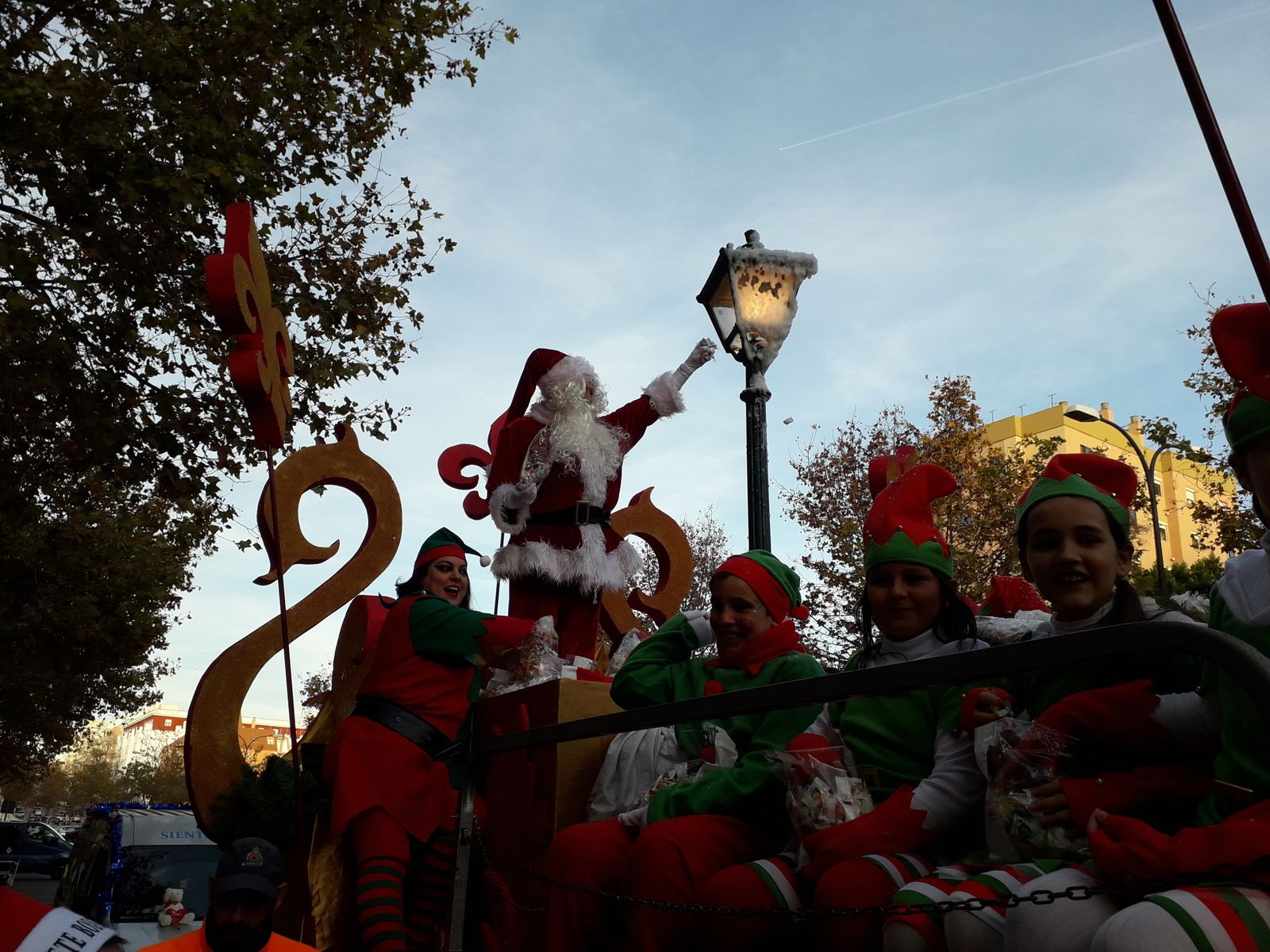 Papá Noel, desde su carroza, arrojando caramelos.