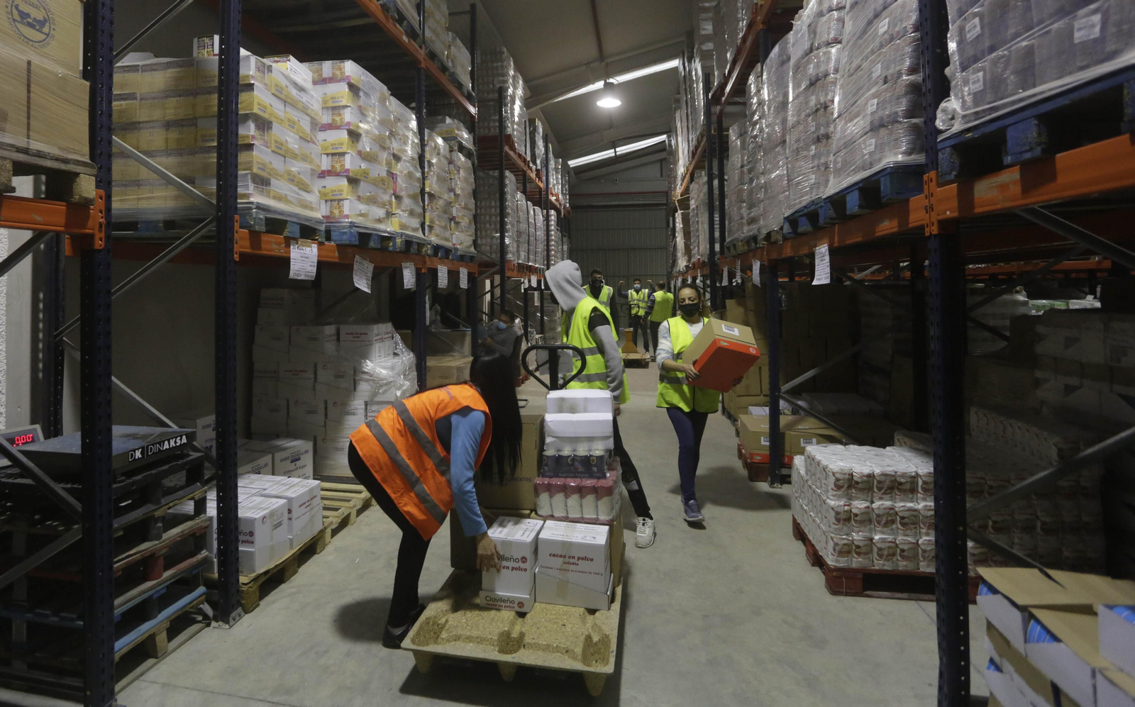 Varios voluntarios organizan los alimentos en el interior de los almacenes en el Polígono Store.
