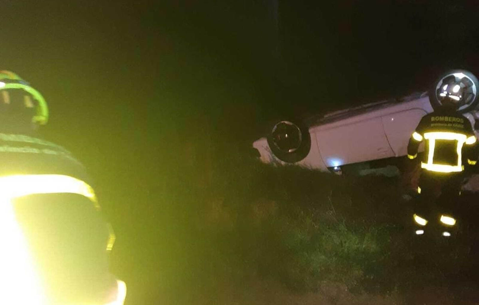Los bomberos inspeccionan el turismo volcado tras el accidente, anoche. Los bomberos inspeccionan el turismo volcado tras el accidente, anoche.