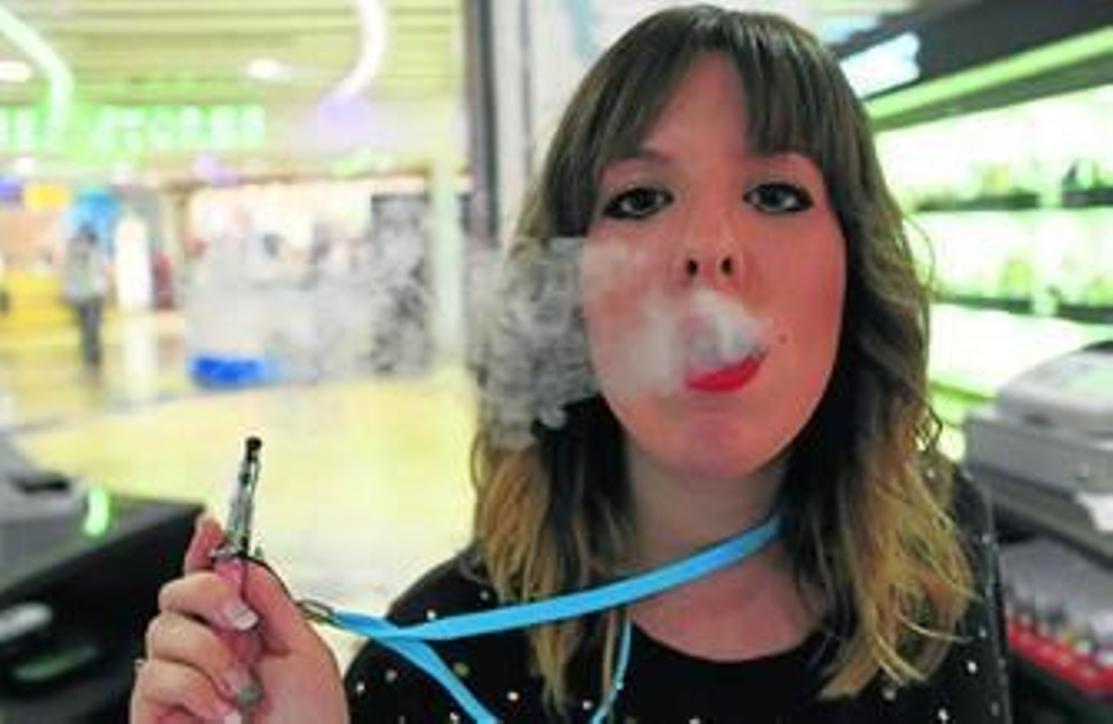 Una chica fuma con el sistema del cigarrillo de vapor dentro de una superficie cerrada.