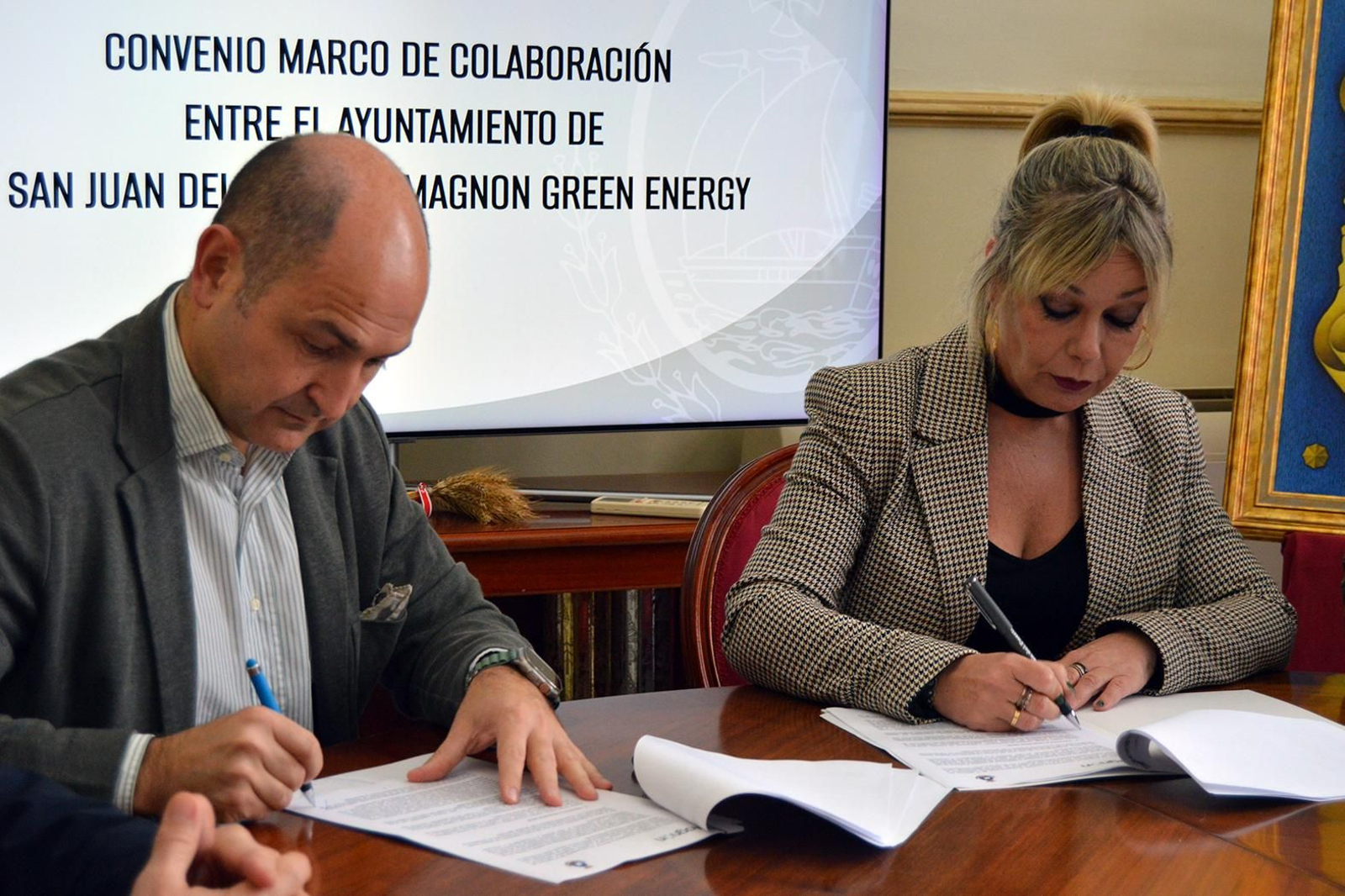 El representante de Magnon Green Energy y la alcaldesa de San Juan del Puerto firman un acuerdo para impulsar una ayuda económica.