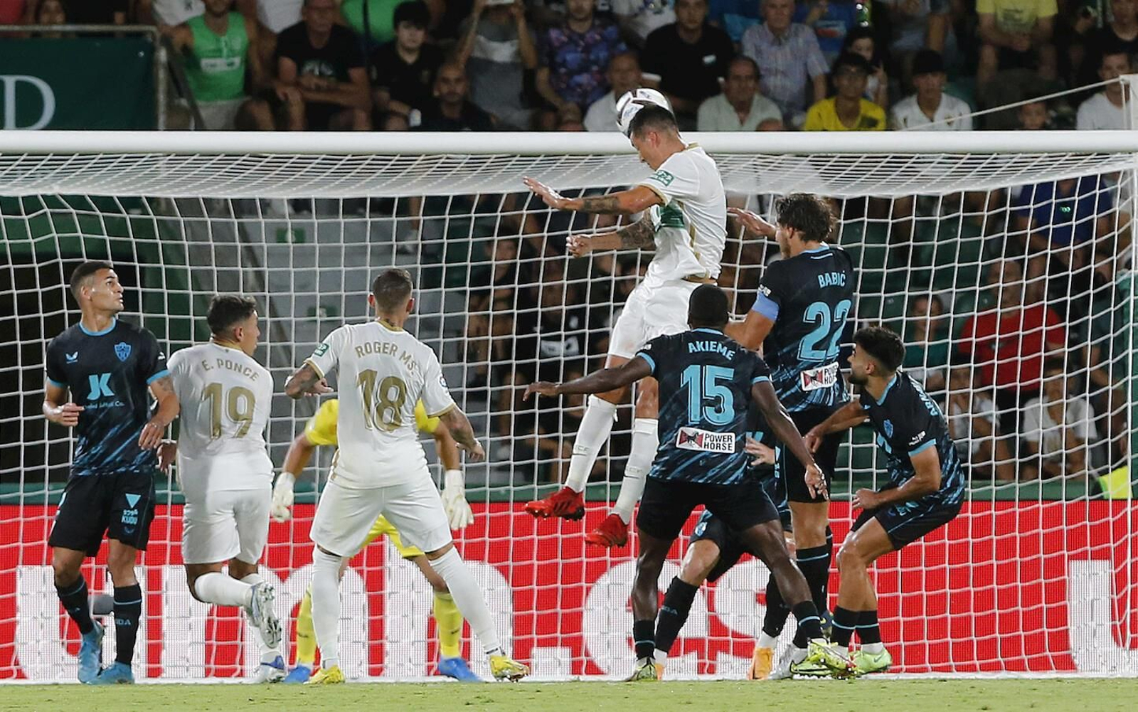 El defensa del Elche  Enzo Roco cabecea un balón rodeado de jugadores del Almería en el encuentro de ida.